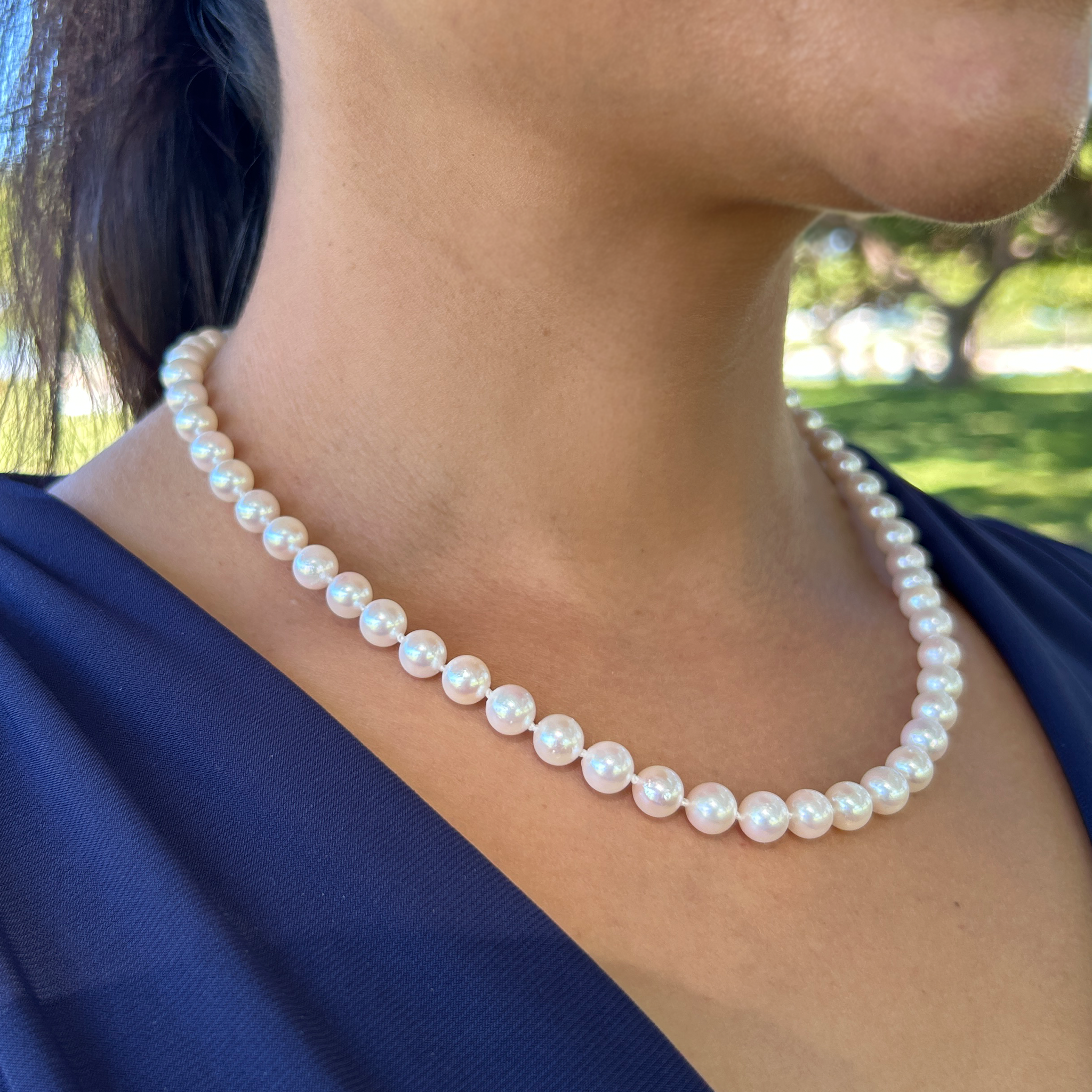 Close-up of an Akoya white pearl strand necklace worn around a woman's neck