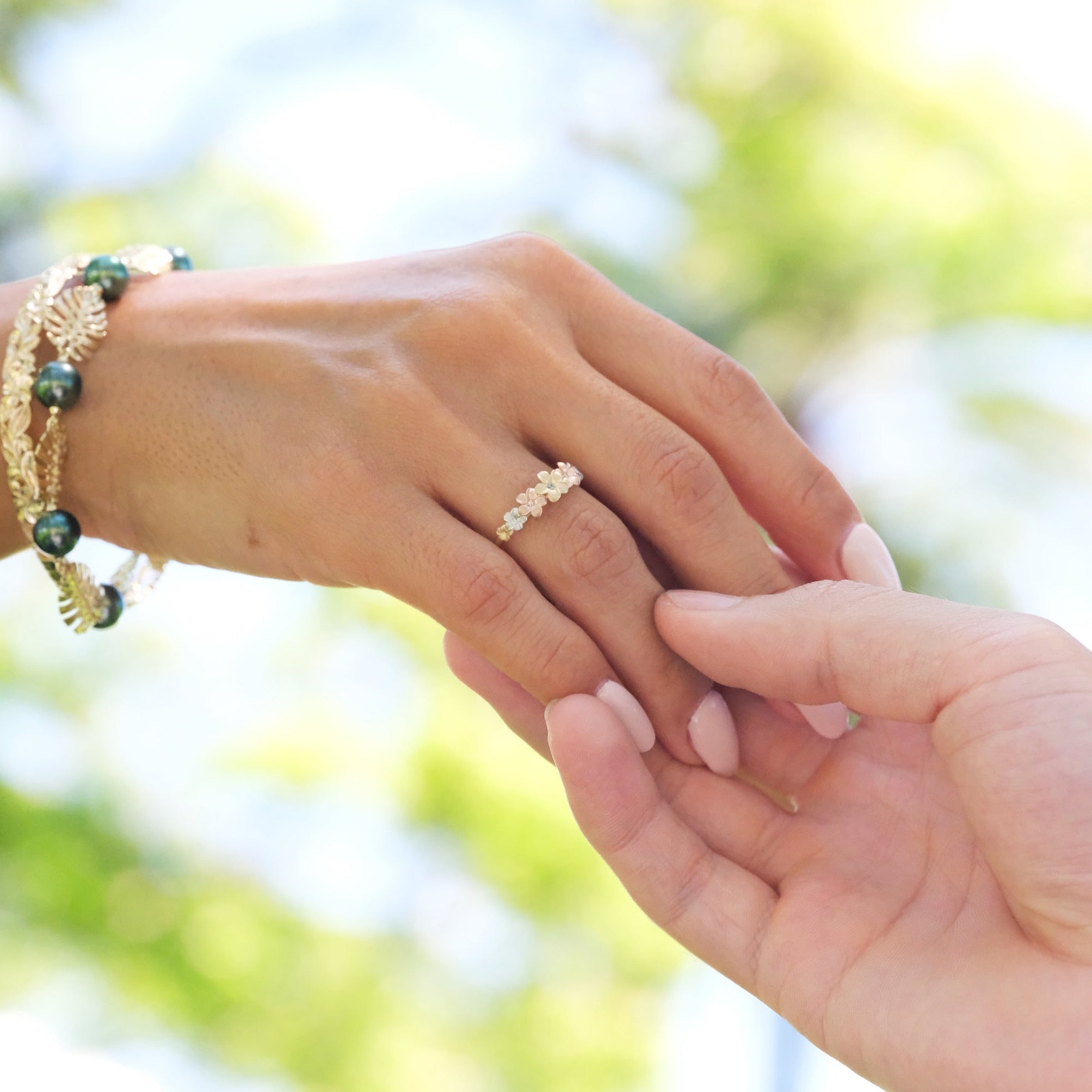 A woman's hand with a Plumeria Ring in Tri Color Gold with Diamonds on it - Maui Divers Jewelry