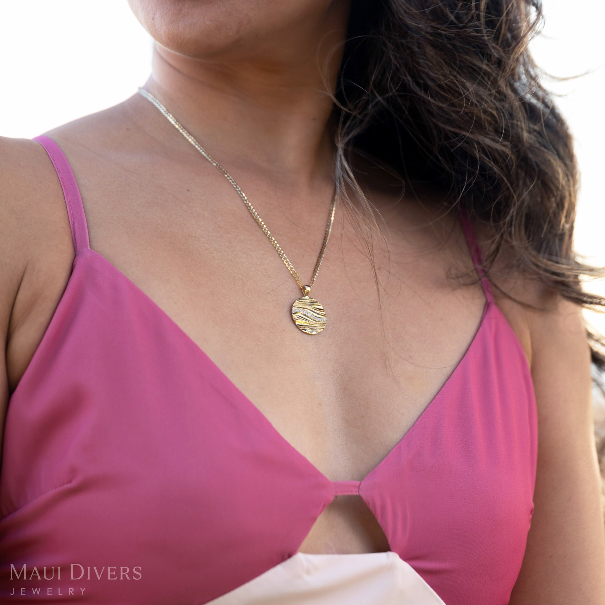 Woman wearing a pink top and the Gold Ocean Sand Pendant 