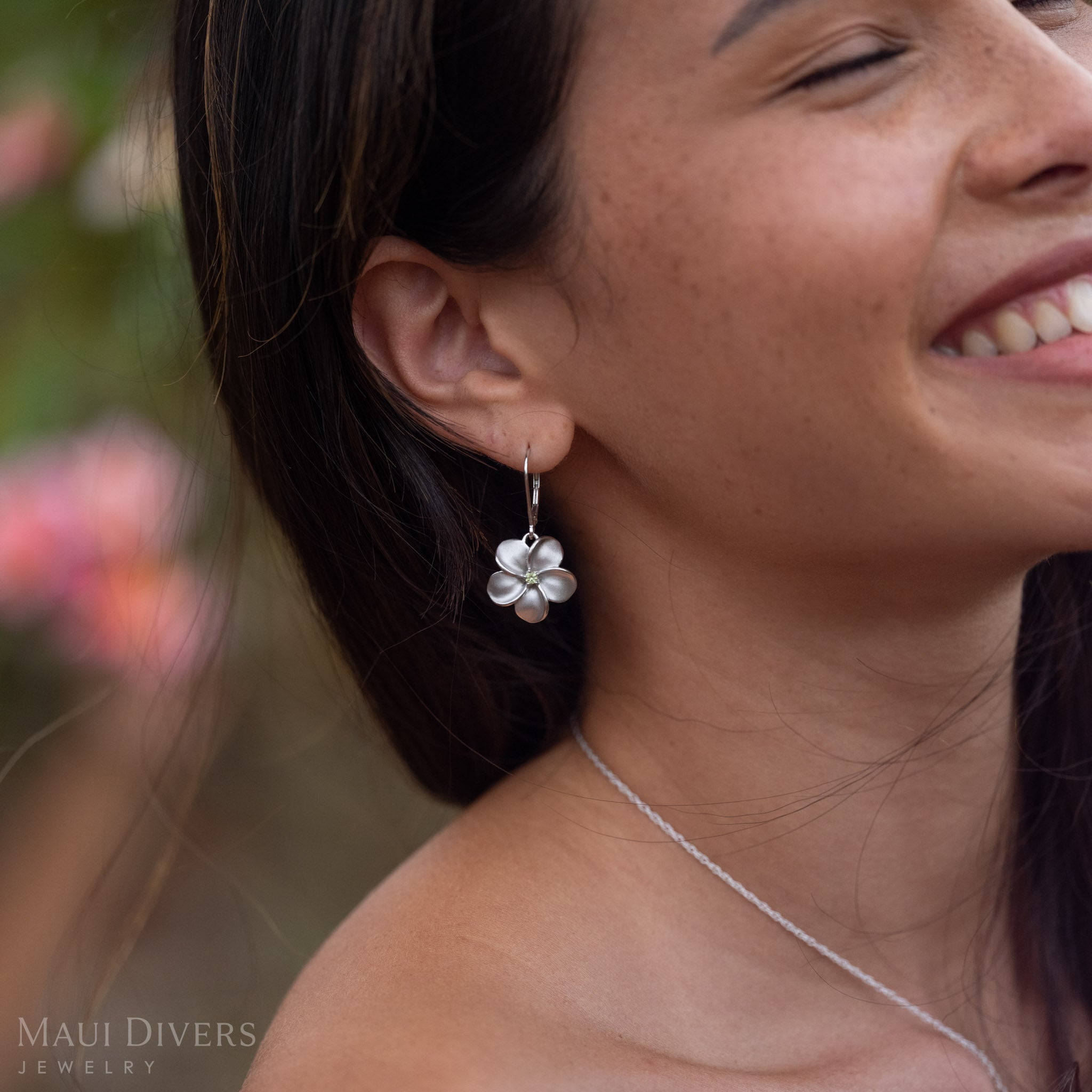 Close-up of woman smiling wearing Peridot Plumeria Earrings in Sterling Silver 