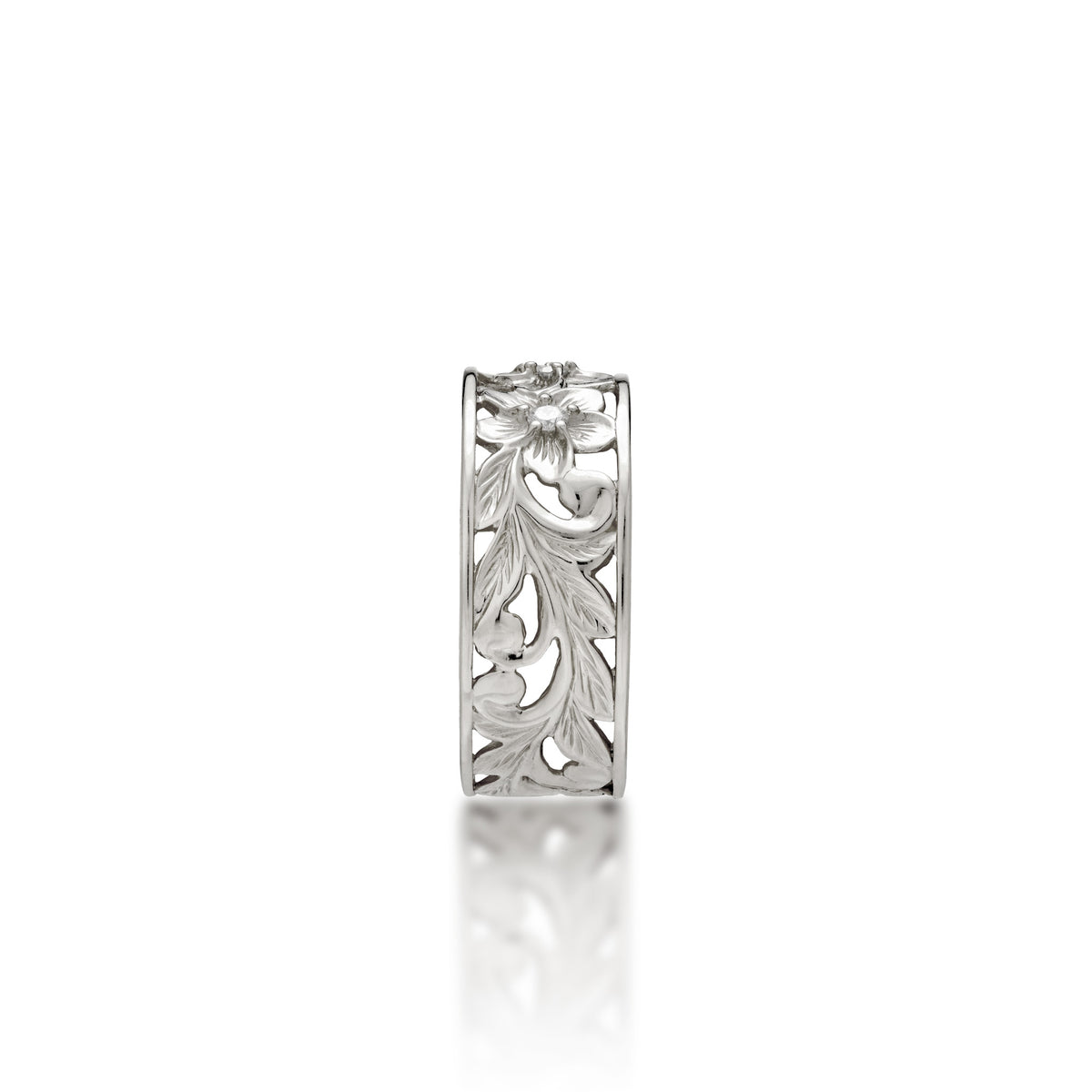A side view of a 14k white gold Hawaiian Heirloom ring with an intricate fern and maile leaf scrollwork pattern featuring plumeria flowers at the top with diamond accents, shown on a clean white background with a soft reflection.