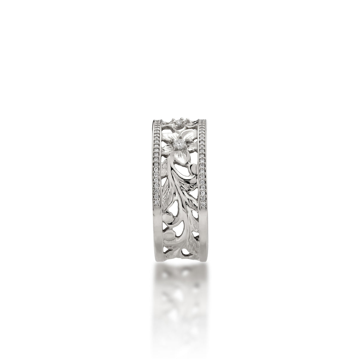 A side view of a 14k white gold Hawaiian Heirloom Ring ring diamond-accented plumeria flowers at the top and fern and maile leaf scrollwork at the bottom and a row of pave set diamonds on each side of the band, shown on a white background