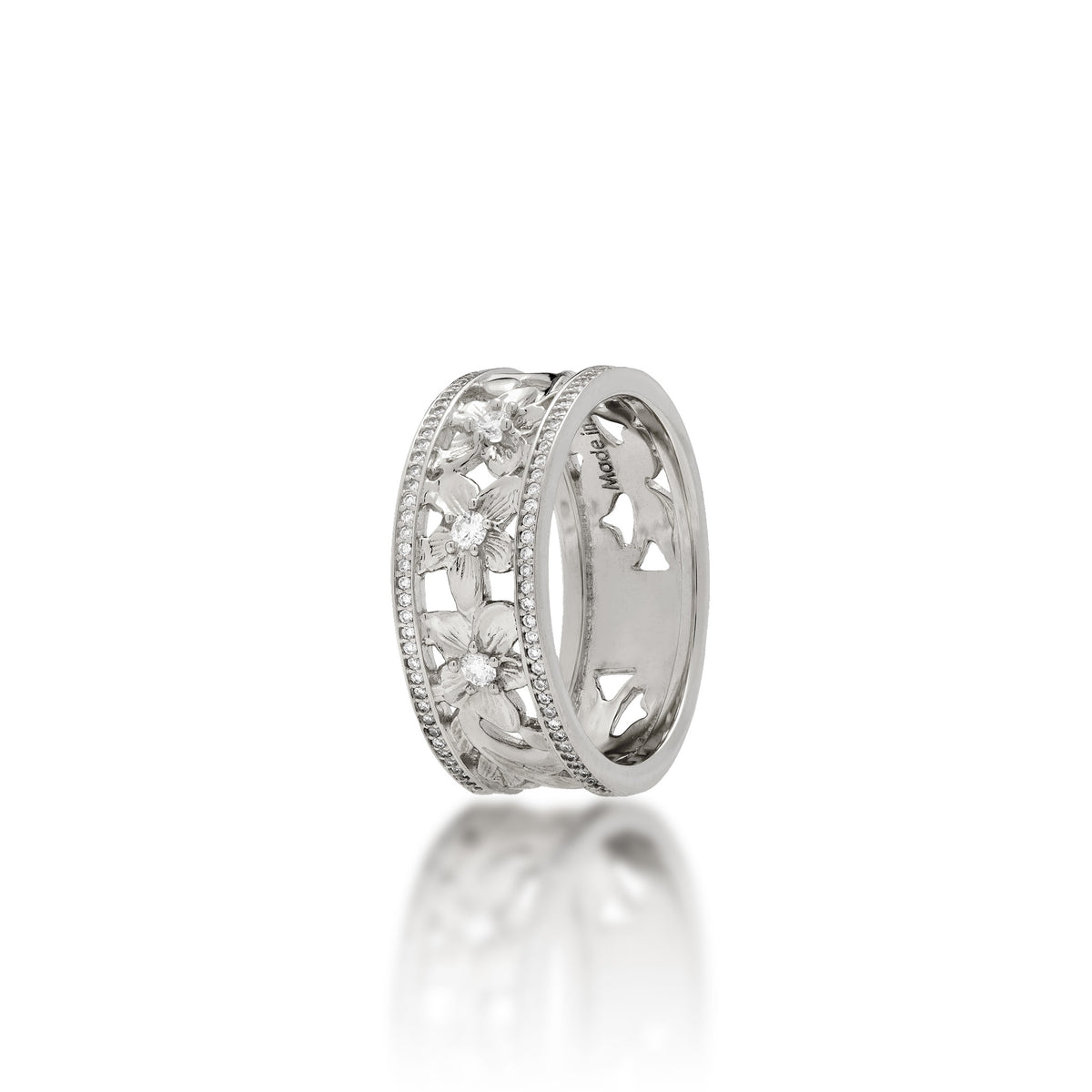A 14k white gold Hawaiian Heirloom ring featuring a row of small pavé-set diamonds on each side of the band and cut-out diamond-accented plumeria flowers at the center, shown on a clean white background with a soft reflection below.