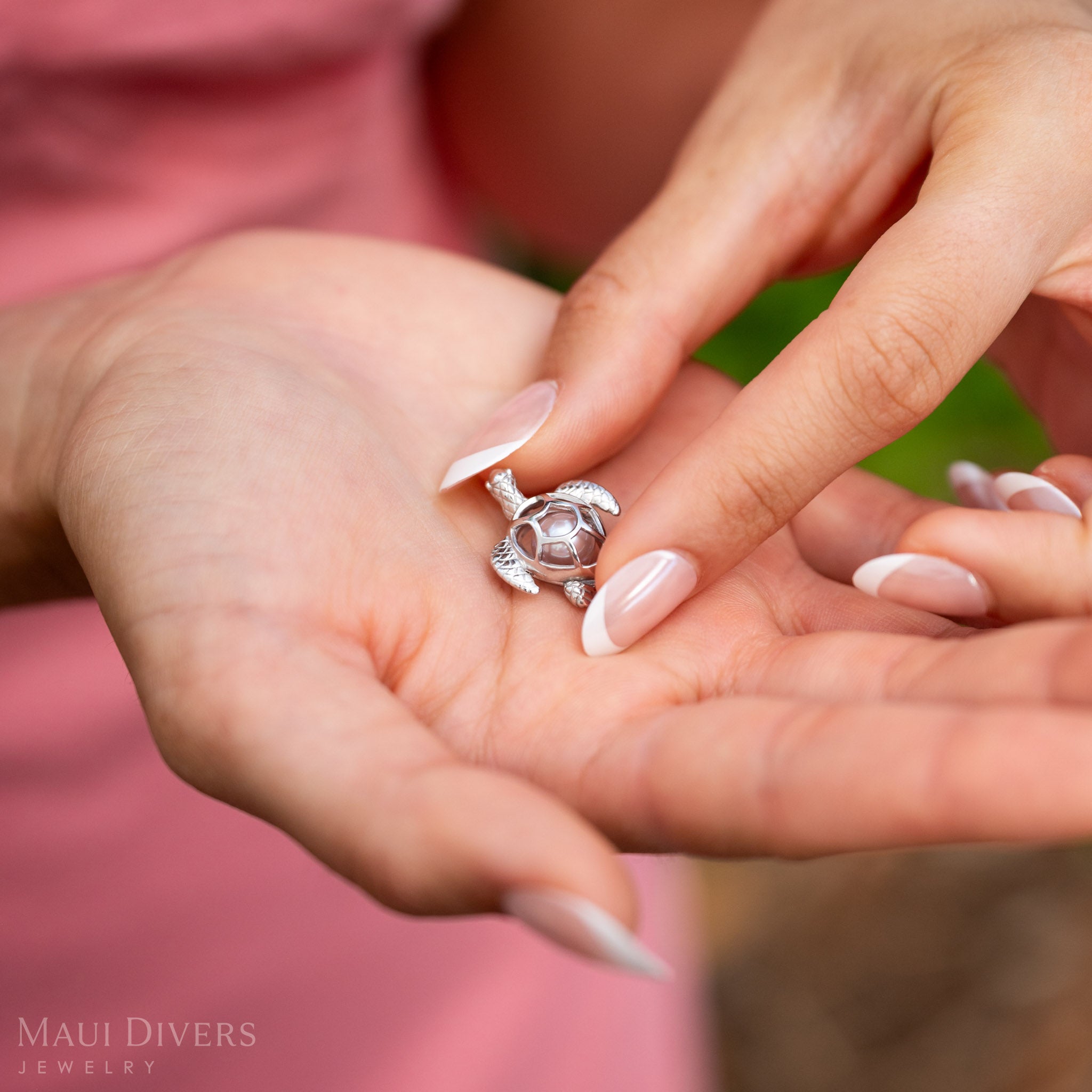 Woman closing a Pearl Honu Pendant in Sterling Silver with a Natural Pink Freshwater Pearl inside.