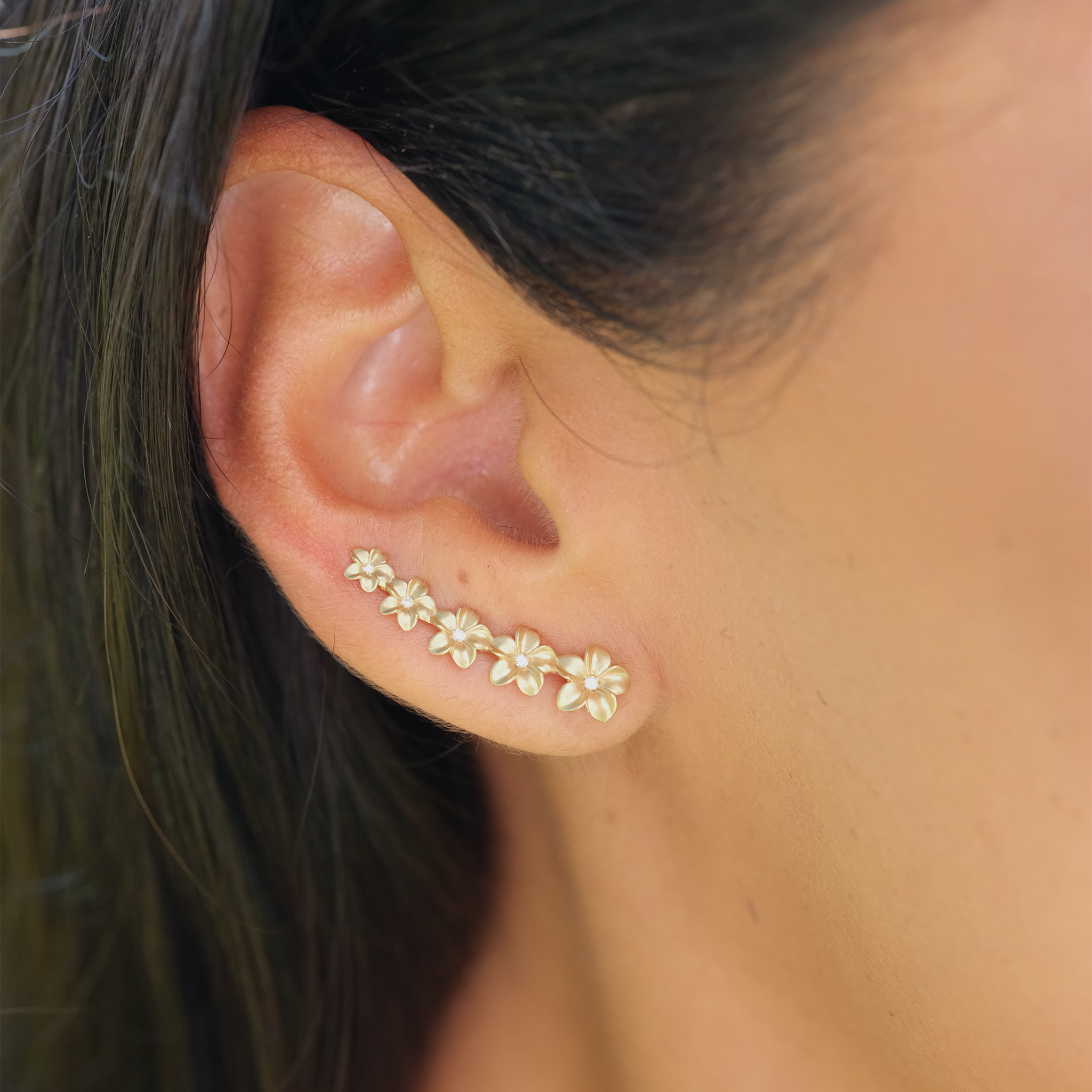 A womanʻs ear with Plumeria Earrings in Gold with Diamonds - 26mm - Maui Divers Jewelry