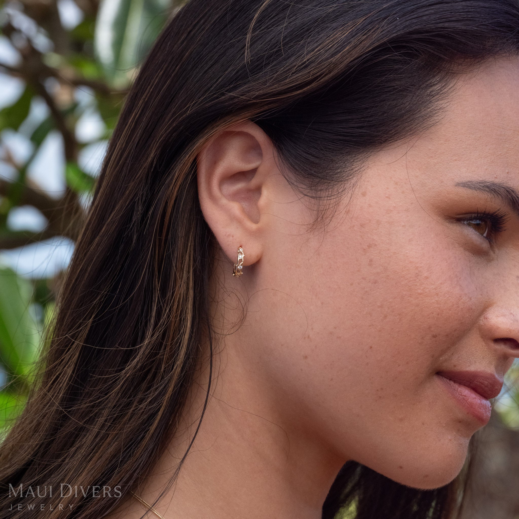 Woman looking outward wearing Heritage Earrings in 14k Gold with Natural Diamonds.