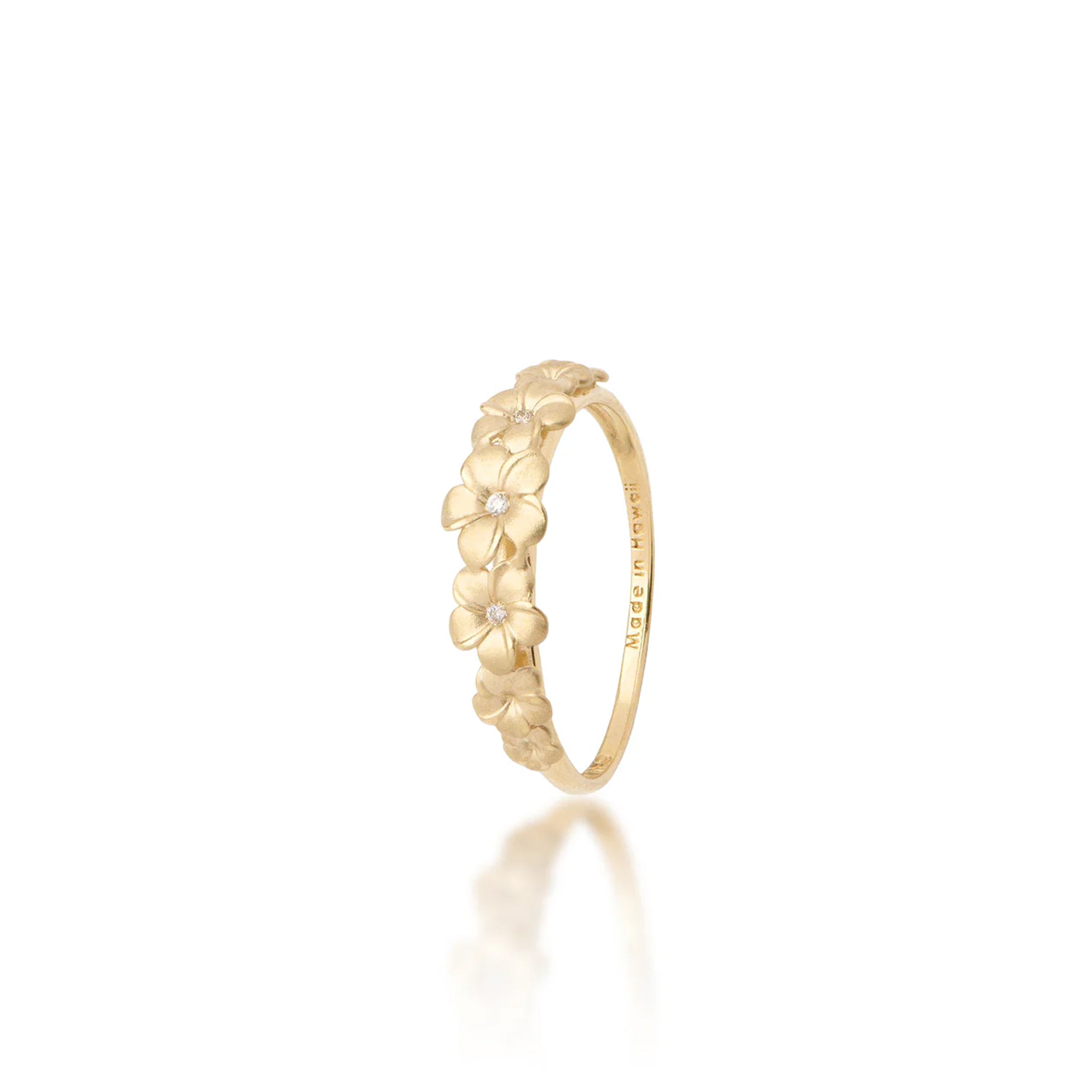 6mm Tapered Seven Satin finished Plumeria Ring in 14k Yellow Gold with a single diamond on each of the three center plumerias and a ʻMade in Hawaiiʻ stamp on the inside of the band against a white background 