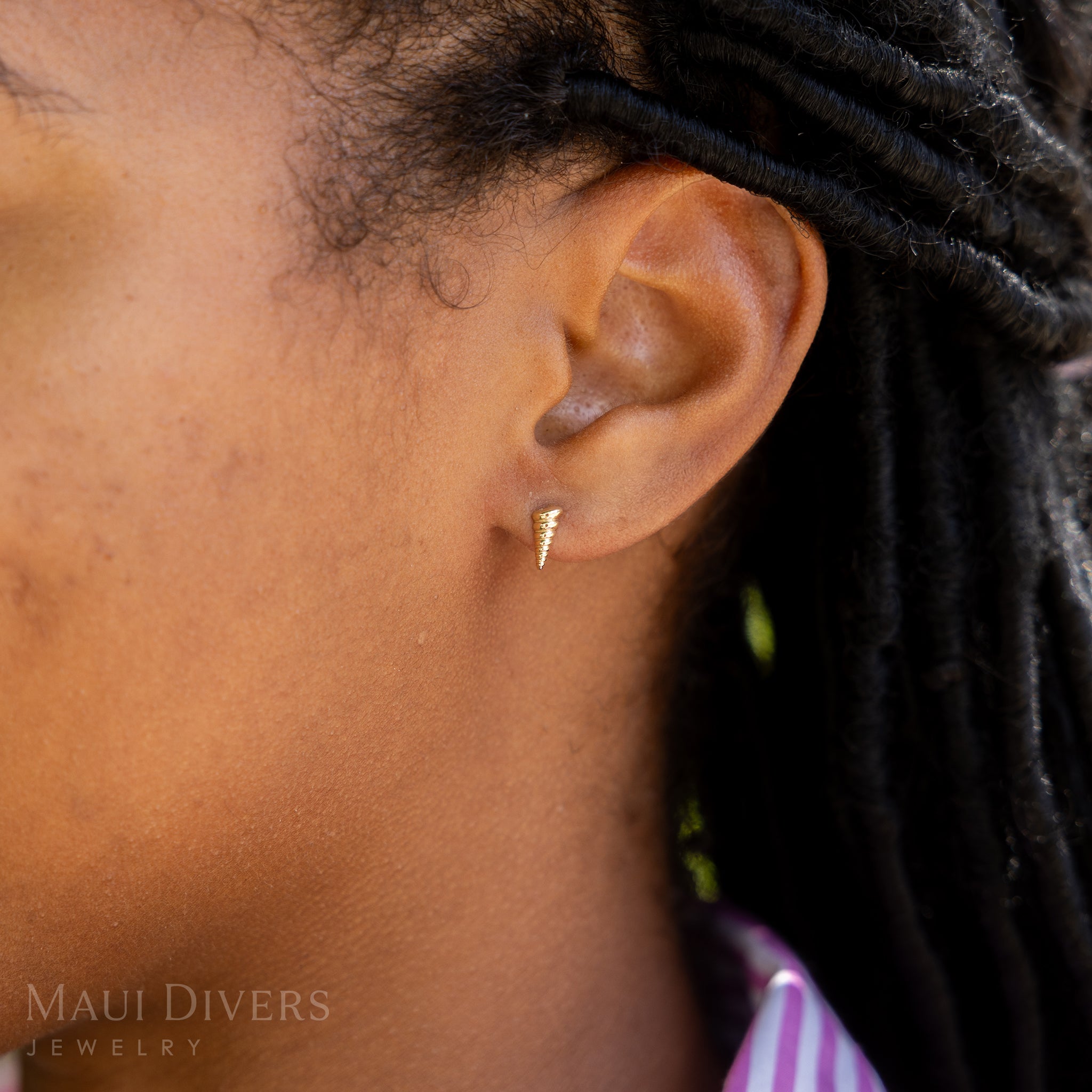 A side view close-up of a woman wearing a Conch Shell Earring in 14k yellow gold