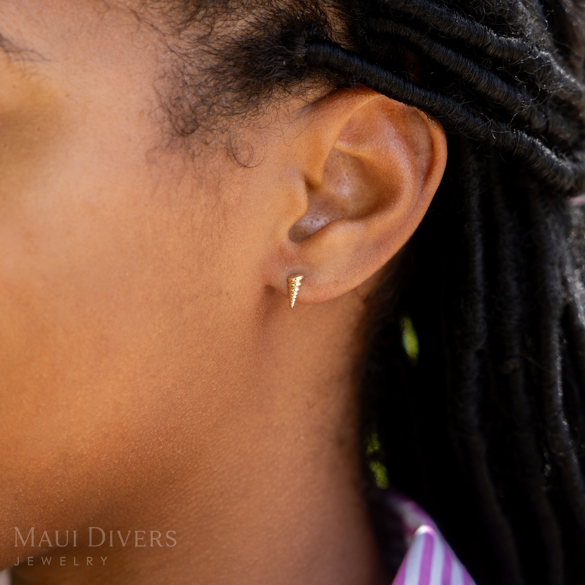 A side view close-up of a woman wearing a Conch Shell Earring in 14k yellow gold