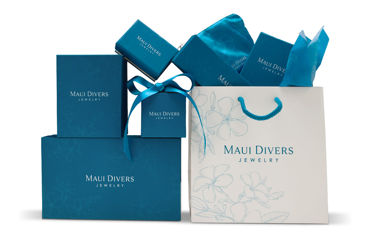 Maui Divers Jewelry gift packaging set featuring blue branded jewelry boxes, a white shopping bag, and blue ribbon accents on a clean white background.