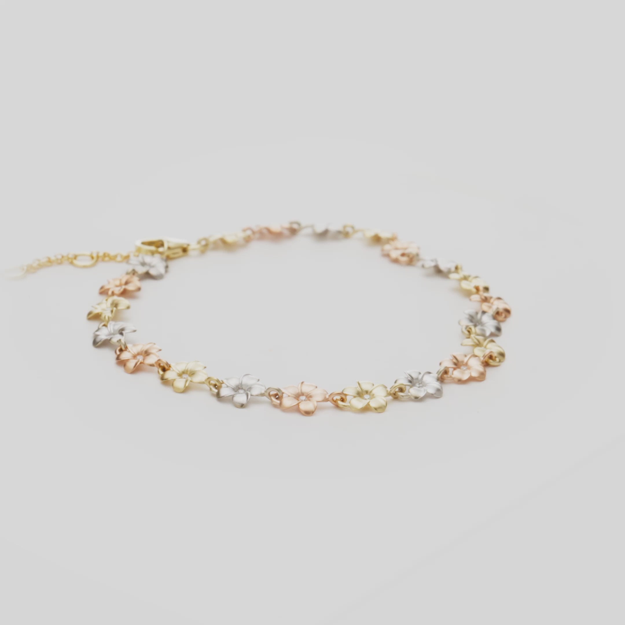 7-8.5" Adjustable Plumeria Bracelet in Tri Color Gold with Diamonds on a white turntable